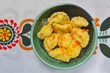 Dumplings, filled with mashed potato in plate on traditional Ukrainian tablecloth. Varenyky, vareniki, pierogi, pyrohy.
