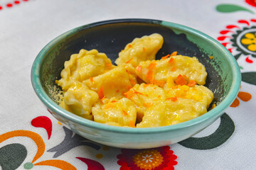 Dumplings, filled with mashed potato in plate on traditional Ukrainian tablecloth. Varenyky, vareniki, pierogi, pyrohy.