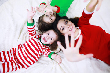A family in striped pajamas is resting at home. Little children dressed as elves are lying on the sofa. Happy family.