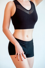 Weight loss. Active lifestyle. Woman sportswear. Workout clothing. Female slim body with thin waist in black bra top shorts isolated on light background.