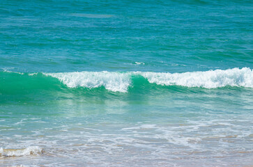 Breaking sea wave on a sandy beach background