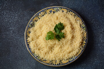 Cooked couscous with green parsley in  ceramic plate