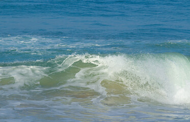 Breaking sea wave on a sandy beach background