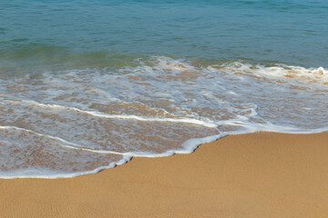 Breaking sea wave on a sandy beach background