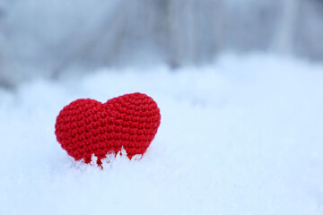 Fototapeta premium Red knitted heart on a snow in winter forest. Background for Christmas holiday, Valentine's card