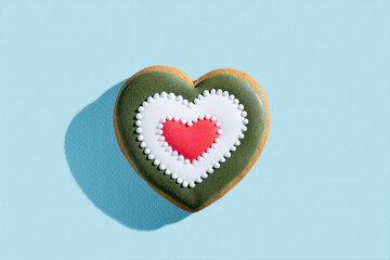 Festive heart shape pastry. Valentines bakery gift. Lovely cookies. Decorated homemade colorful icing gingerbread biscuit isolated on blue pastel.