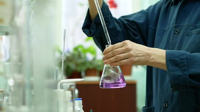 chemical laboratory slow motion mixing of ingredients in a flask reaction with fiolet color clouse up