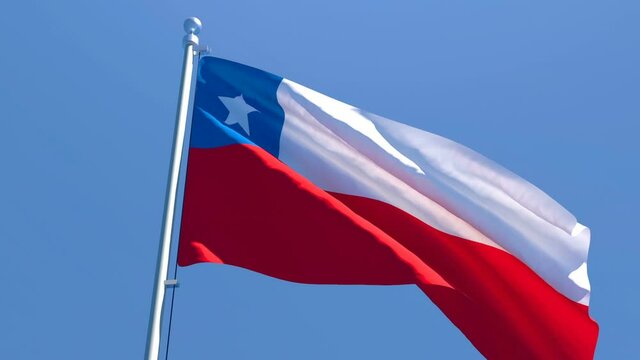 The national flag of Chile is flying in the wind against a blue sky