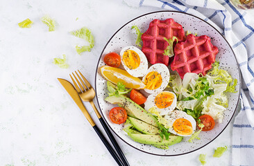 Breakfast with beetroot waffles, boiled egg, tomato and slice avocado on white background. Appetizers, snack, brunch. Healthy food. Top view, overhead, copy space