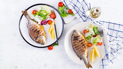 Delicious grilled dorado or sea bream fish with salad, spices, grilled dorada on a plate. Top view, overhead, copy space