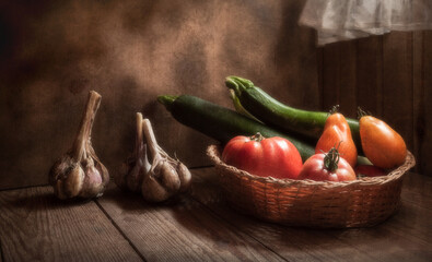 Still life with vegetables - garlic, tomatoes, zucchini, basket. On a natural wooden background.
