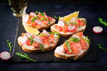 Sandwich with salted salmon for healthy breakfast on dark background. Fish menu.