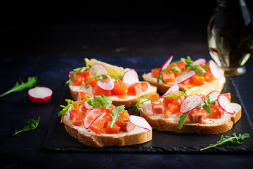 Sandwich with salted salmon for healthy breakfast on dark background. Fish menu.