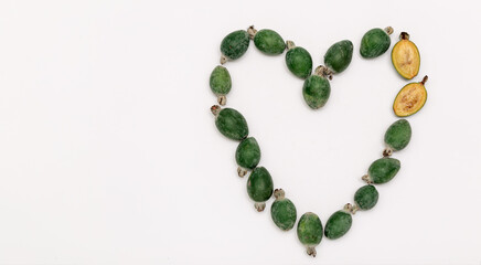 Feijoa heart shape on white background. Vitamin, immunity, recipe concept. Top view, copy space, flat lay