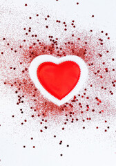 Red confetti glitter in shape of heart on white festive background, copy space, valentines day festive card