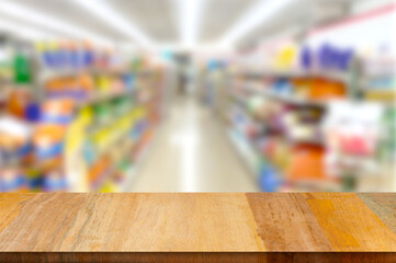 An empty wooden table against the backdrop of a supermarket shelf