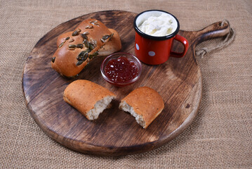 Pastry breakfast with jam and cheese on wooden background with burlap