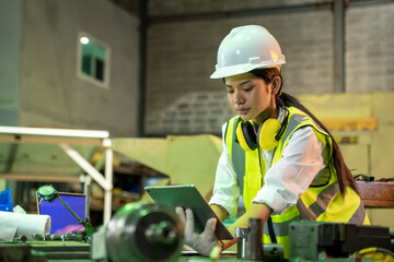 Female technician worker using a digital tablet working and checking production in a large industrial factory.