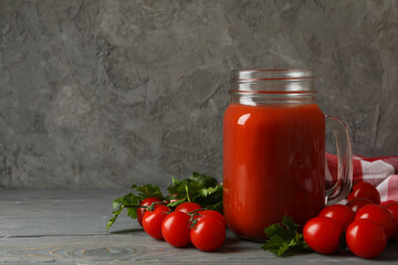 Jar of tomato juice, tomatoes and kitchen towel on wooden background