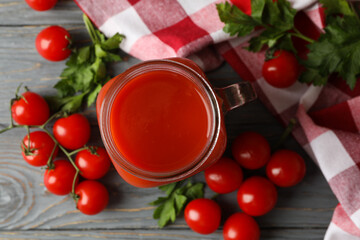 Jar of tomato juice, tomatoes and kitchen towel on wooden background