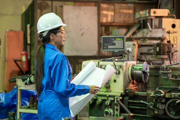 Industry engineer woman looking paper plans for planning work at factory.