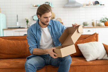 Fototapeta na wymiar Happy man customer unpacking cardboard box receive open post mail delivery package