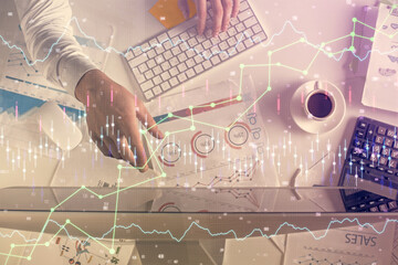 Multi exposure of man's hands typing over computer keyboard and forex graph hologram drawing. Top view. Financial markets concept.