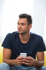  man looking away while using smartphone on blurred foreground