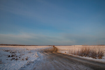 Winter roads of the North. Dirt frozen uneven road stretches through many kilometers of snow.