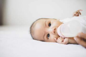 Adorable little asian newborn baby sleeping and drinking milk on a comfortable bed in the morning
