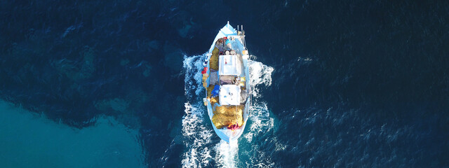 Aerial drone ultra wide photo of traditional wooden fishing boat with fishermen cruising Aegean...