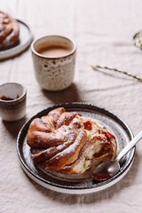 Cinnamon swirl brioche or Cinnamon roll bun and cups of cocoa on greige linen tablecloth. Homemade baked swedish cinnamon roll. Kanelbullar. Cozy winter breakfast