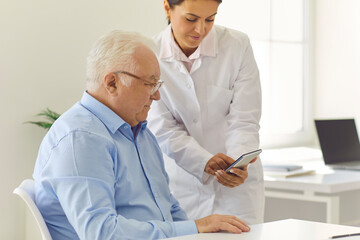 Nurse teaches old man to use phone app for setting medication reminder or tracking health indicators