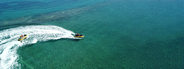 Naklejka premium Aerial drone ultra wide photo of jet ski watercraft with couple cruising in high speed in Caribbean tropical exotic turquoise crystal clear sea