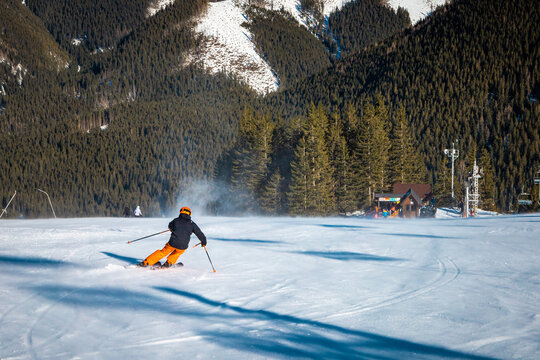 Young man going quickly down the slope leaving snow trail behind him
