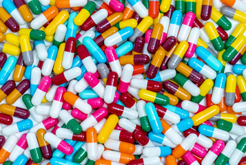 Many capsule pills. Top view capsule pills. Full frame blue, yellow, green, pink, red, orange, white, and gray capsule pills. Healthcare and medicine concept. Pharmaceutical industry. Health budget.