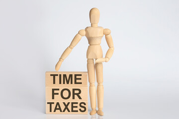 Wooden man shows with a hand text TIME FOR TAXES concept on wooden block