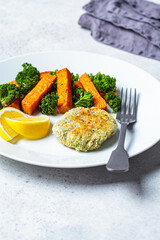 Vegetarian food concept. Vegetable fritter with baked sweet potato and kale on white plate.