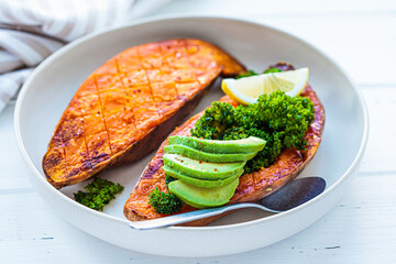 Baked sweet potato halves with salad and avocado. Healthy vegan food concept.