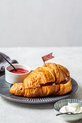 Valentine's day concept. Fresh croissant with cream and berry jam on gray plate, copy space.