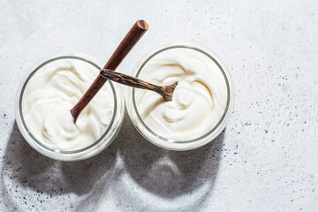 Homemade yogurt in glass jars, light background, copy space, top view. Yoghurt preparation concept.