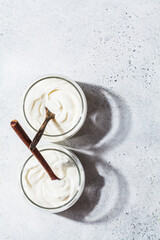 Homemade yogurt in glass jars, light background, copy space, top view. Yoghurt preparation concept.