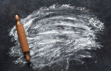 Flour and dough with a rolling pin on the kitchen table. New Year's pastries. Layout of ingredients for making a gingerbread man.
