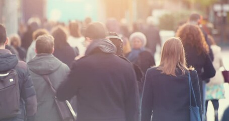 Blurred people commuting in central business district at rush hour with morning sun light. Walking commuters going to work in downtown's crowded streets, 4k video footage