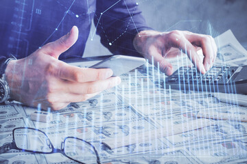 Double exposure of man's hands holding and using a digital device and forex graph drawing. Financial market concept.