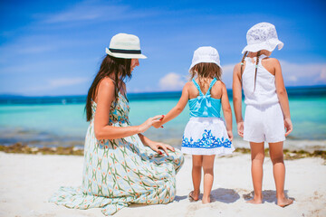 Adorable little girls and young mother on tropical white beach