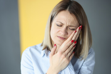 Young woman closing eyes and holding cheek with hand