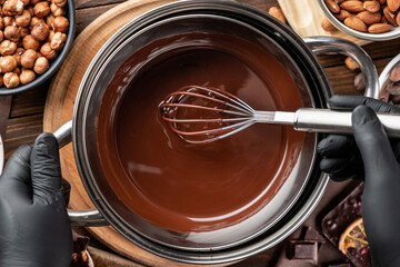 Hand stirring melted dark hot chocolate in a metal bowl. Process of cooking home made chocolate. Chocolate glaze.