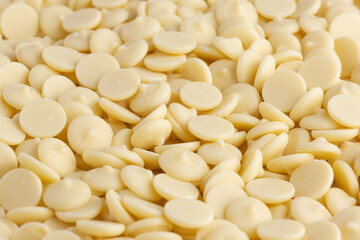 White chocolate chips or granules background. Confectionery white chocolate.