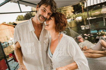 Senior couple dancing on a party outside drinking wine.